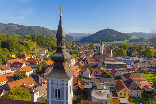 Der Kirchturm der Rupertikirche im Vordergrund und dahinter die Häuserlandschaft und die Berge